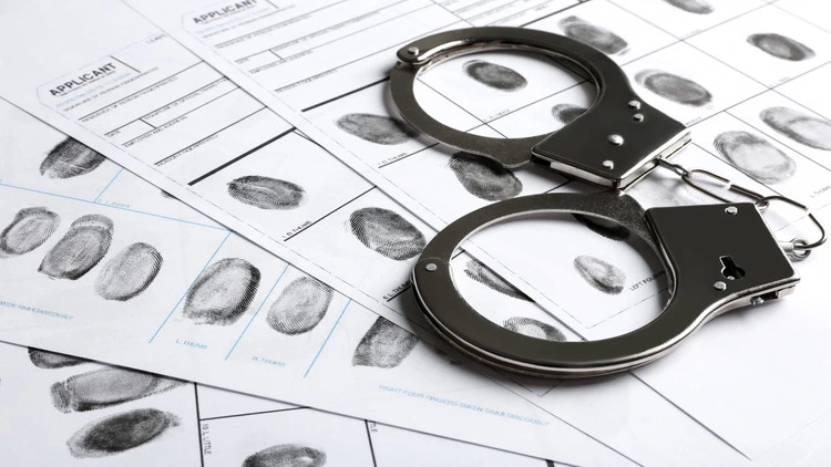 Closeup image of a handcuffs and fingerprint records sheet.