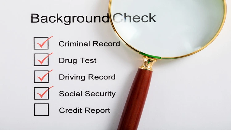 An image of a magnifying glass over a background check form.