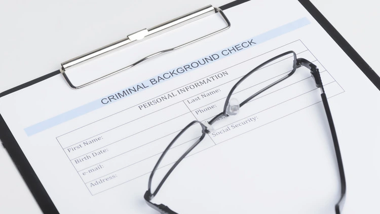 An image of criminal background check form with eyeglasses on it.