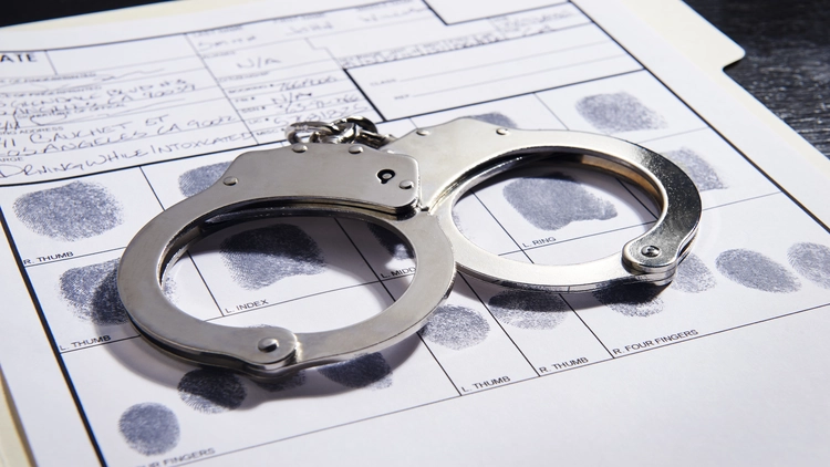 An image showing a pair of handcuffs placed on top of a fingerprint record sheet.