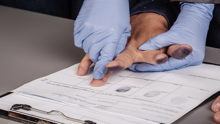 An image showing a person's hands collecting fingerprints on a fingerprint record sheet.