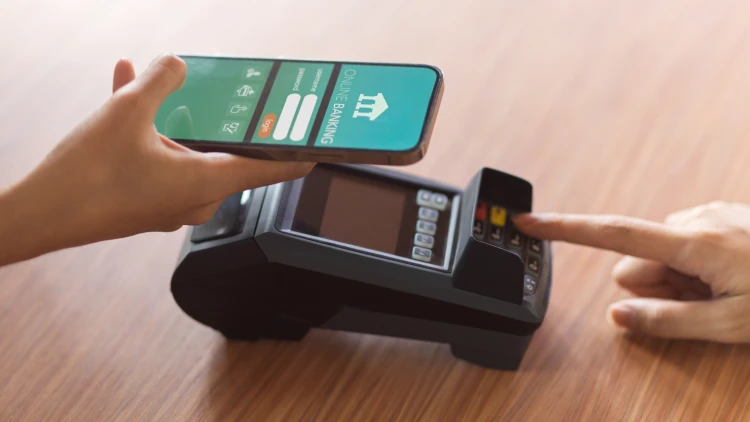 Using online banking app for payment, receiving receipt via payment terminal on desk.