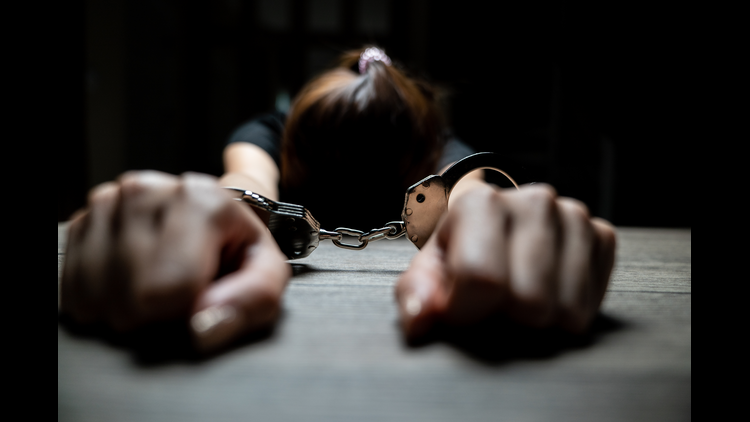 A women prisoner handcuffed in the dark prison.