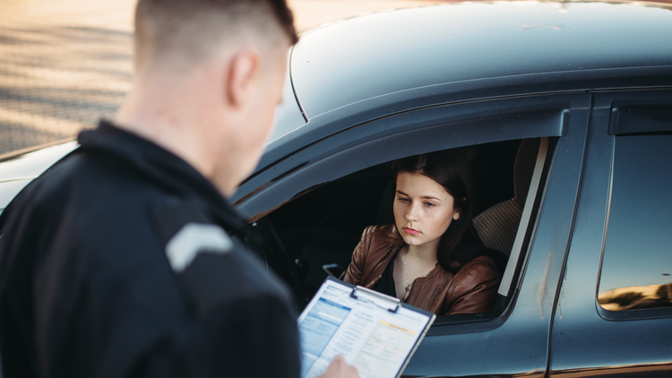 Police officer issuing a traffic ticket to a young woman driver