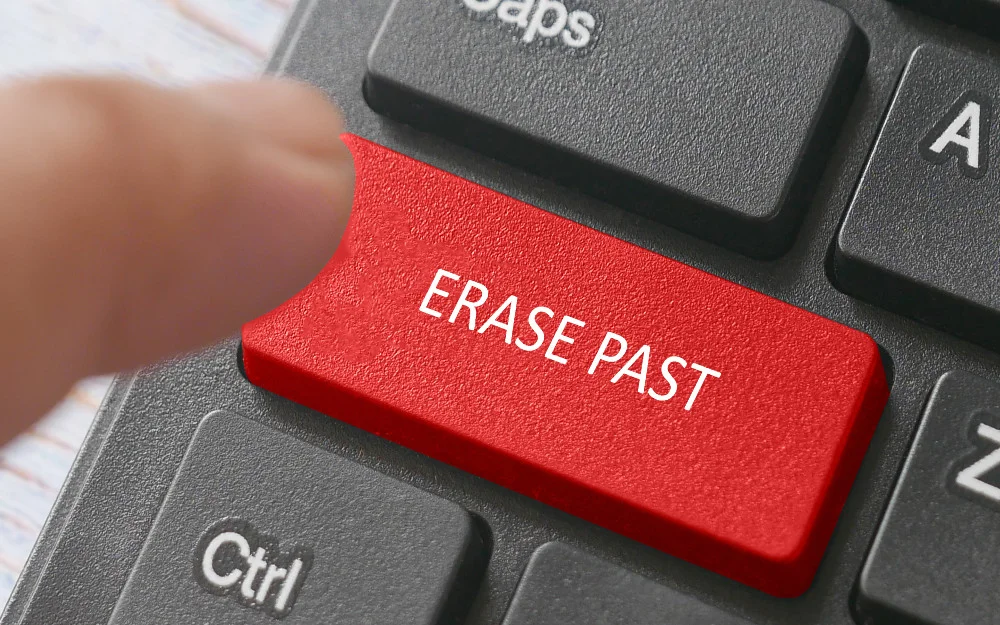 Finger hovering over a computer keyboard with a red button that says erase past. 