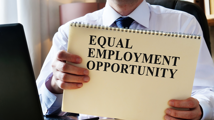 A person holding a notepad with "Equal Employment Opportunity" written on it, representing fair hiring practices.