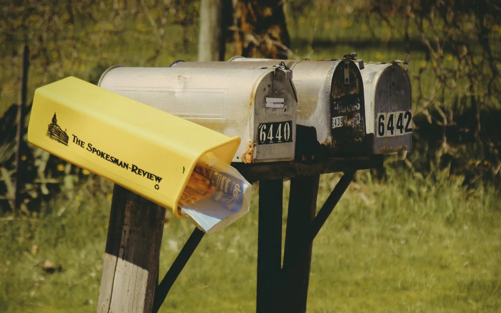 Three old grey mailboxes showing address numbers that can be used in reverse address searches. 