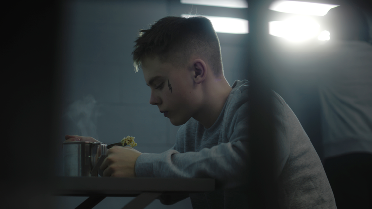 A teenager eating inside a juvenile detention center.