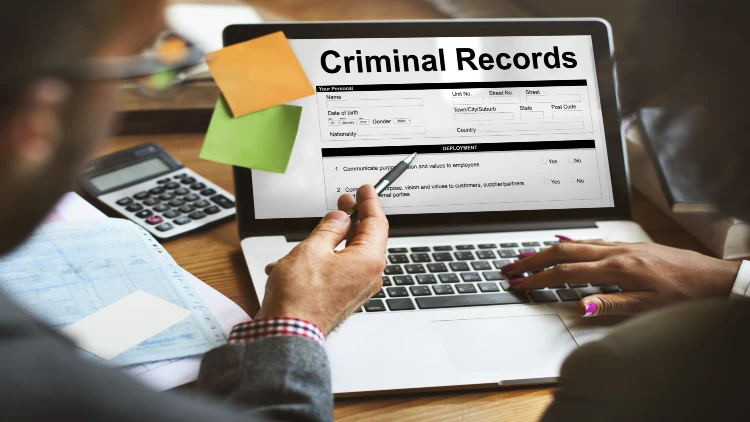 Man and woman viewing criminal records on laptop screen.