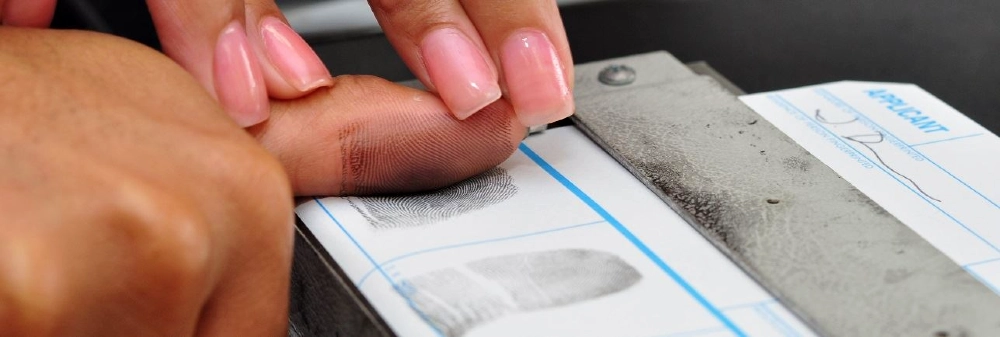 Woman fingerprinting a man's thumb. 