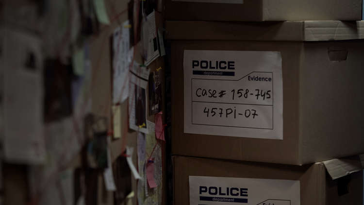 Close up view of police case files in a box beside an investigation board.