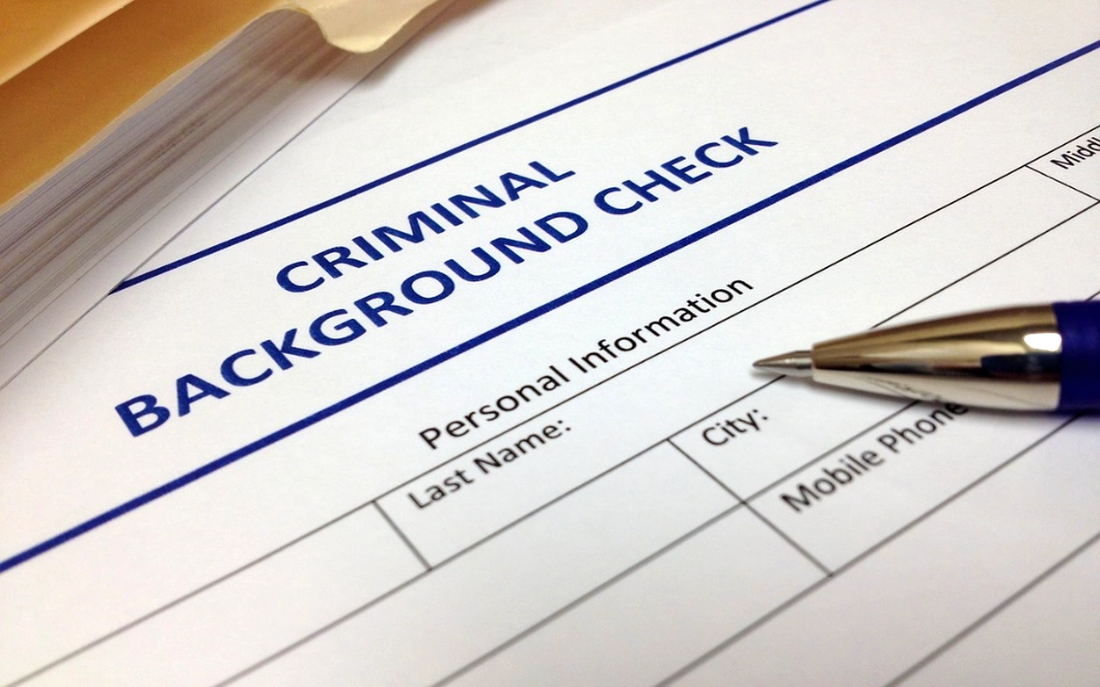 Criminal background check application with pen answering the question do you have to pay for a background check and if so, how much for a background check. 