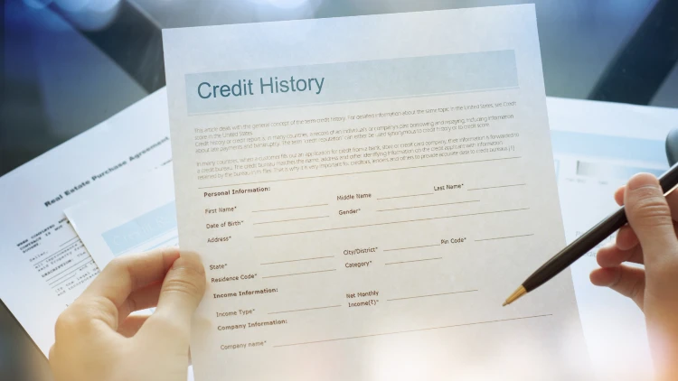 Close-up view of a credit history form on the left hand and a pen on the right.