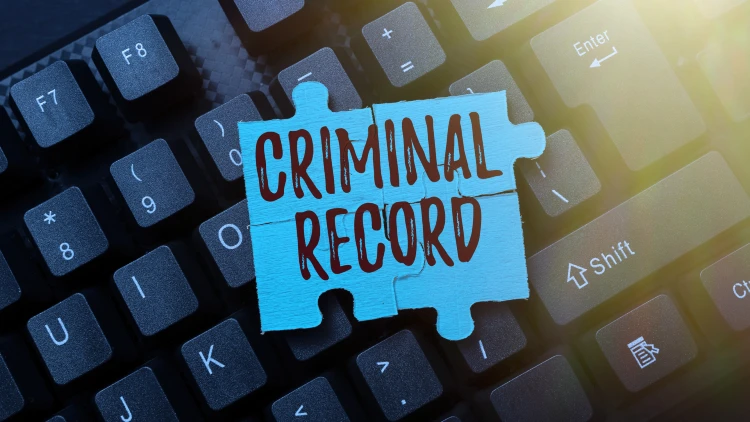 A blue puzzle piece with "CRIMINAL RECORD" written on it is placed on a black computer keyboard.