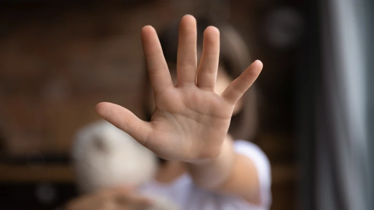 Close-up of a little girl with her hand raised in a 'no' gesture, protesting against domestic violence.