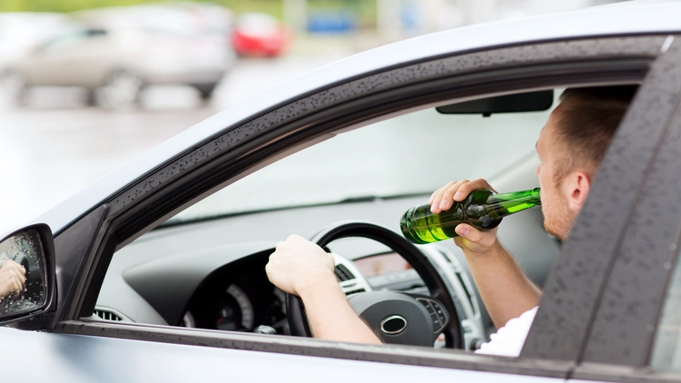 A person drinking from a bottle while driving.
