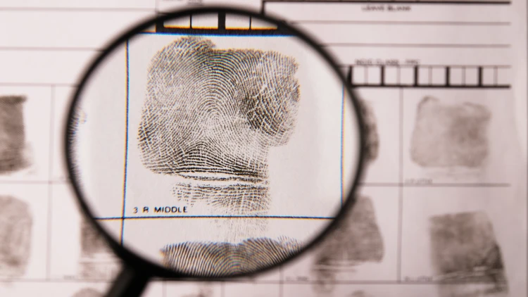 Fingerprint on a fingerprint card under a magnifying glass.