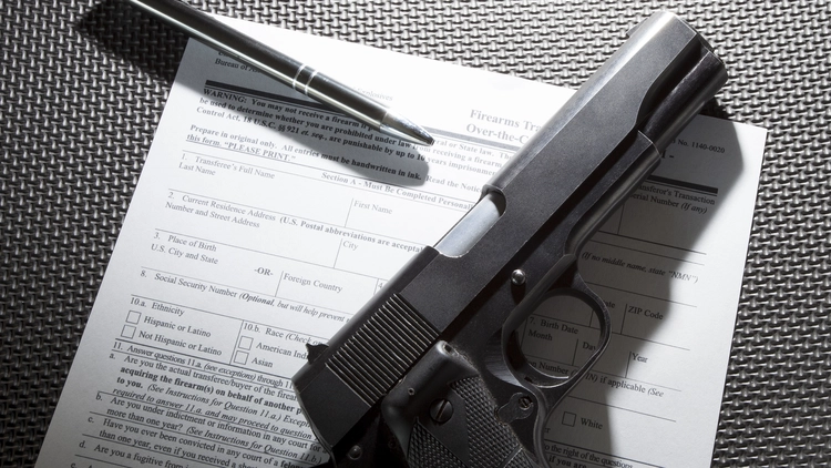 An image of a firearm transaction record with a handgun and a pen.