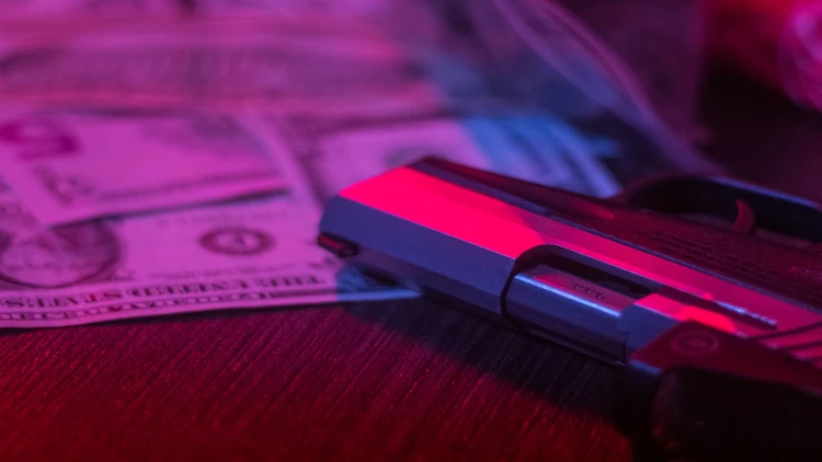 Close-up view of a gun and money on the table.