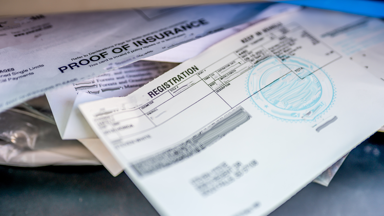Close up image of insurance and vehicle registration documents in a desk.