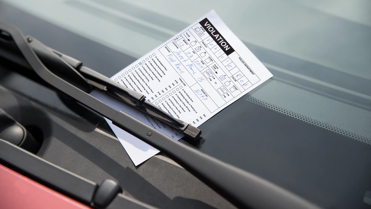 Close-up of parking ticket on car's windshield.