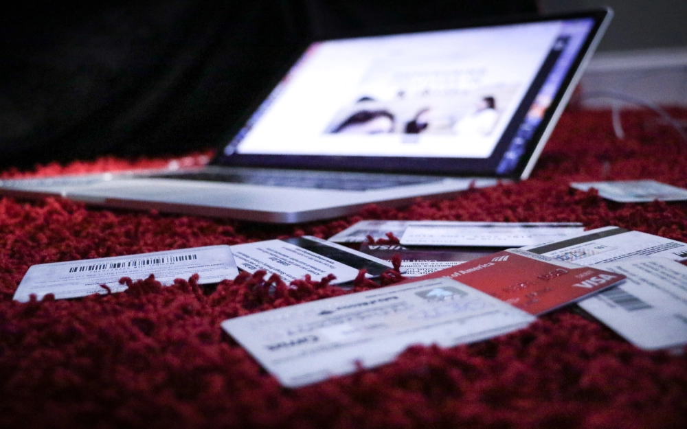 Image of a laptop and many credit cards on red shag carpet outlining the fisrt step for how to run a rental background check on myself by going online to get a free credit report. 