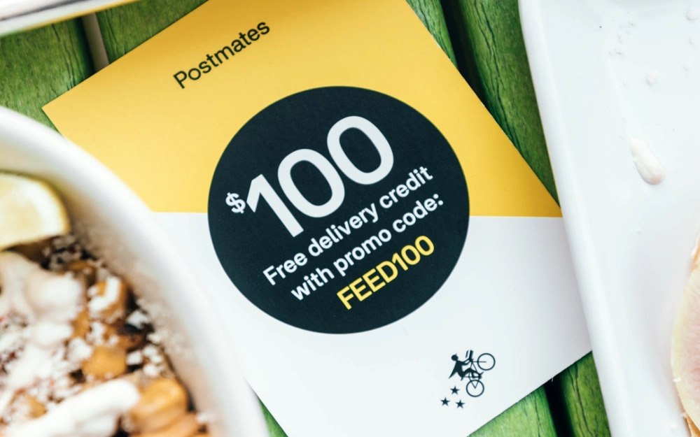 Promo code close up of POstmates delivery credit that can feed 100 people while using postmates although some some people wonder does postmates hire felons to delver food? 