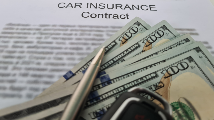 Close up of a car insurance document with a pen, car keys and money on top indicating the cost of car insurance.