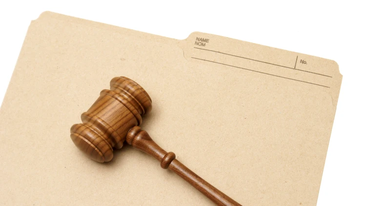 Close up image of a court gavel on a brown document folder