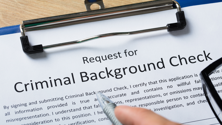 A form for requesting a criminal background check with a pen lying on top.