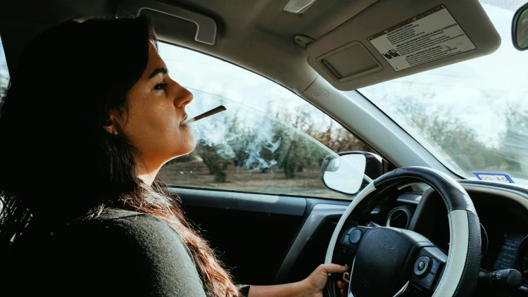 Image of a woman driving while under the influence and smoking