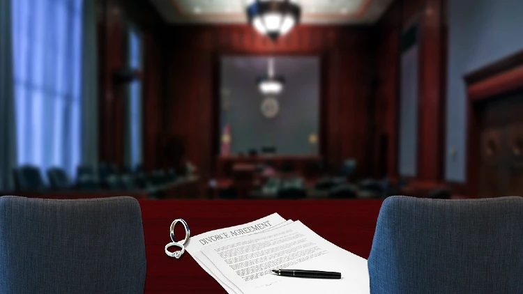 Image of divorce agreement, rings, a pen on a table in a court room
