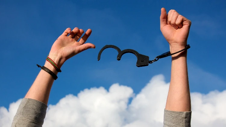 Image of hands raised up with handcuff unlocked