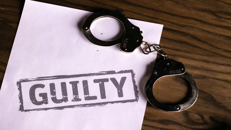 Image of guilty stamp on a paper and handcuff