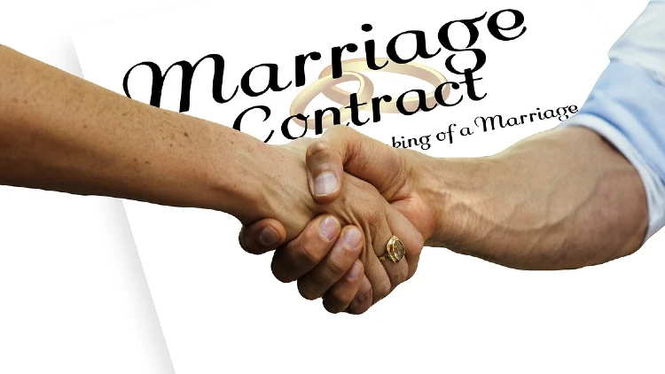 Image of two hands having a hand shake in front of a marriage contract