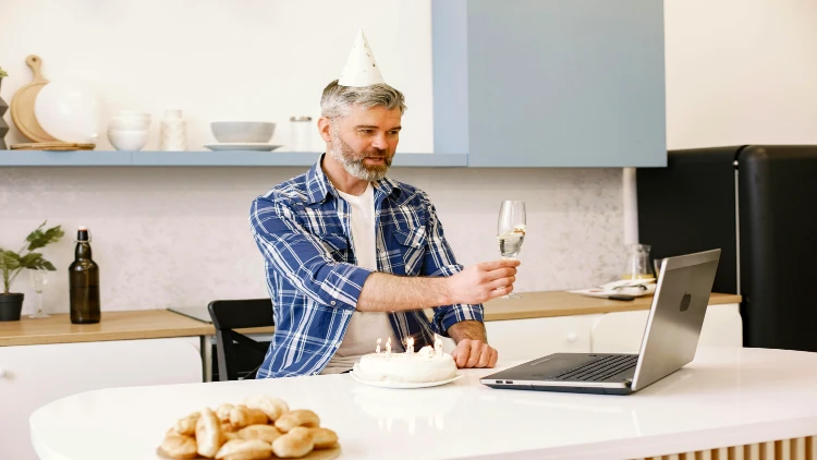 Image of a man celebrating birthday and toasting with someone online