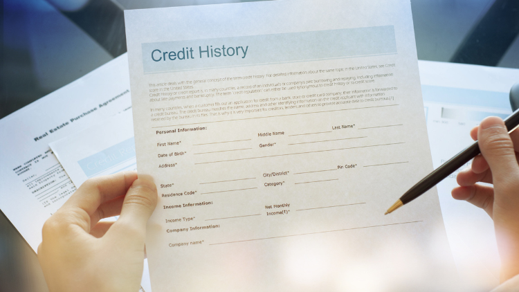 Close-up view of a credit history form on the left hand and a pen on the right.