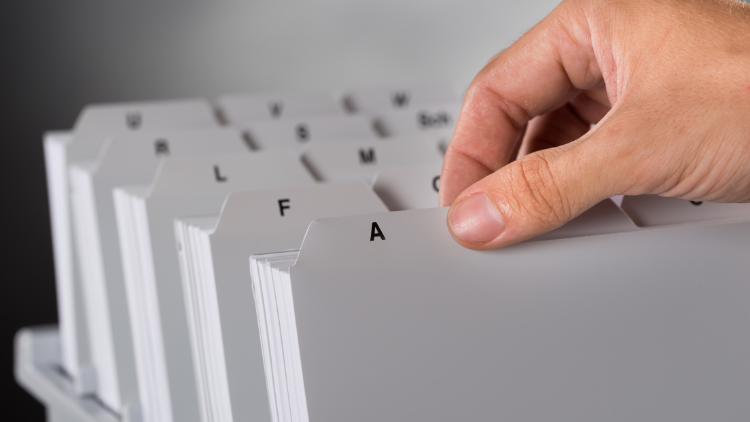 Close-up view of a hand holding one of the neatly arranged files of documents.