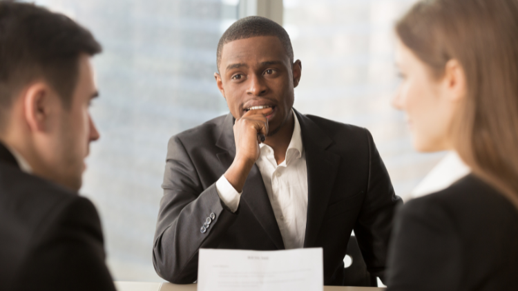 Three people in business attire are examining a resume.