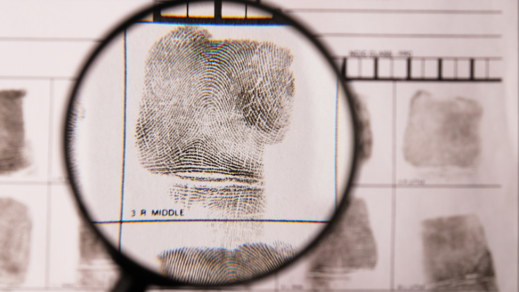 Close-up view of a fingerprint card with a magnifying glass on top.