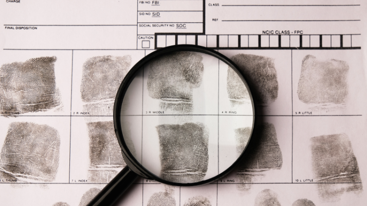 Fingerprint on a fingerprint card under a magnifying glass.