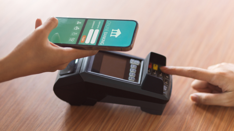 Using online banking app for payment, receiving receipt via payment terminal on desk.